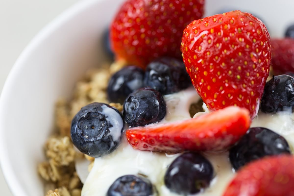 Tigela de iogurte natural com granola, morangos e mirtilos