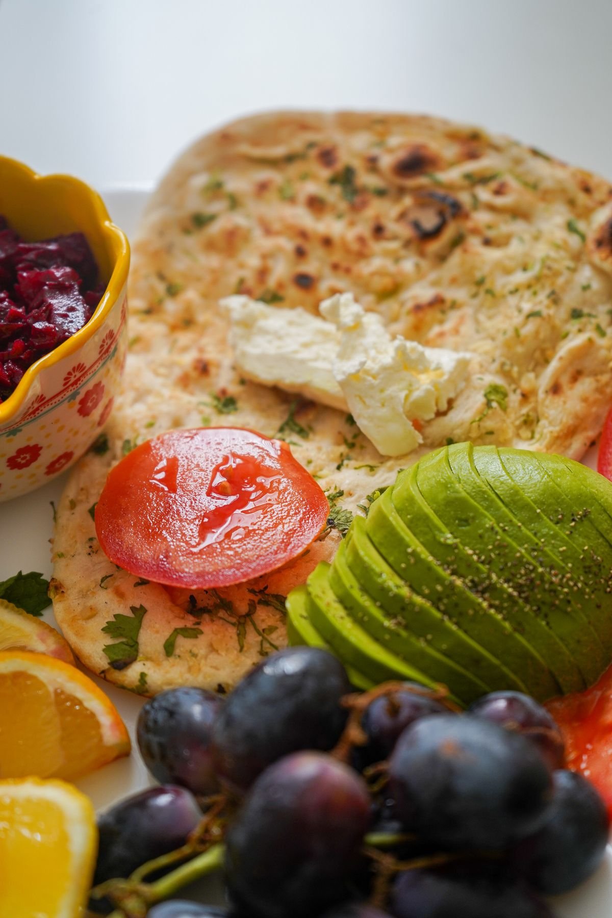 Prato colorido de café da manhã com pão, abacate, tomate e uvas